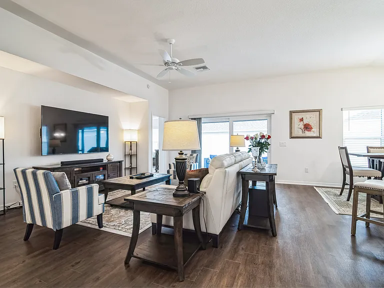 The Living Room Area with a Ceiling Fan, with access to the Master Bedroom and Sliding Door to Cagebird/Lanai.