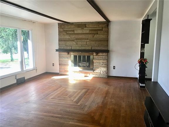 The Living Room has a large stone fireplace and large front window letting in the sunshine.  The hardwood floors were made by th