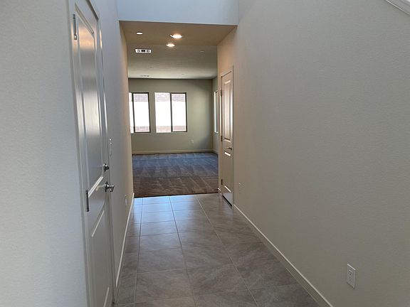 Enter into a large hallway with the garage door to the left and staircase on the right.