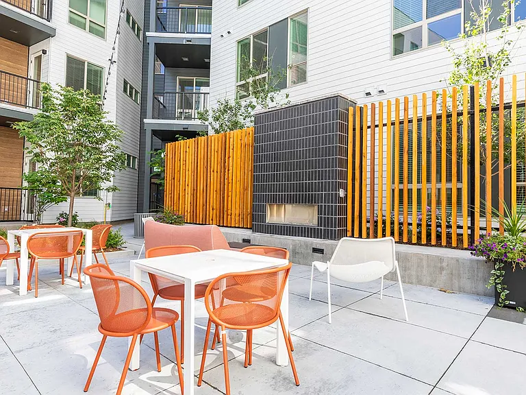Enjoy outdoor gathering spaces with modern seating, dining tables, and a cozy fireplace in the landscaped courtyard.