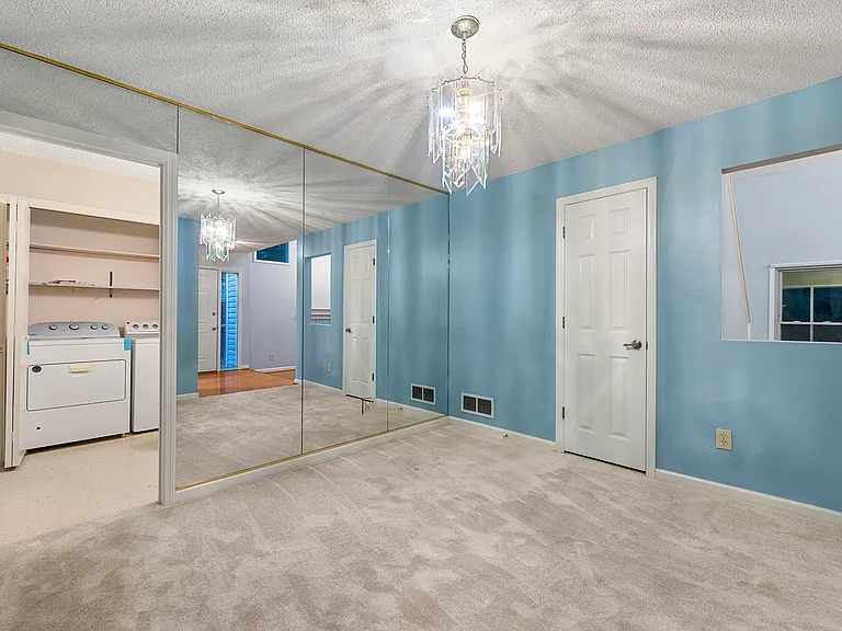 Dining room, with a large mirrored wall. The open door on the left is towards the guest bathroom and the laundry room which closes as well. The door on the right is the coat closet. Opening to the downstairs living room.
