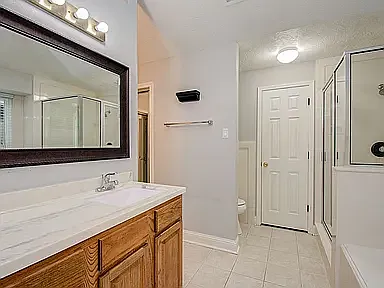 Bright master bath with quartz countertop, large mirror, soaking tub, separate shower, and walk-in closet.