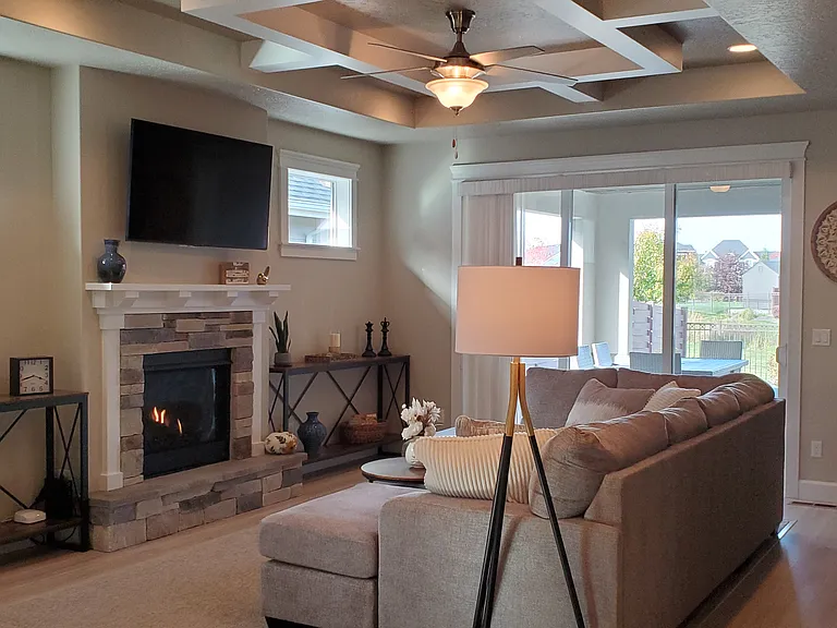 INVITING FRONT LIVING ROOM WITH GAS FIIREPLACE AND LARGE PATIO WINDOW SLIDER TO PATIO AND VIEW OF HILLSDALE CREEK.