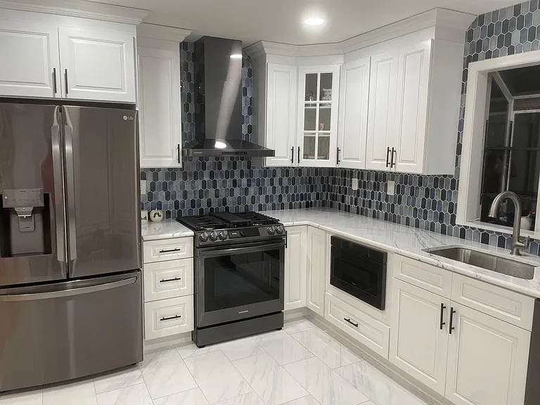 New and updated top-of-the-line refrigerator, range, hood, drawer microwave, and dishwasher with a glass tile backsplash.