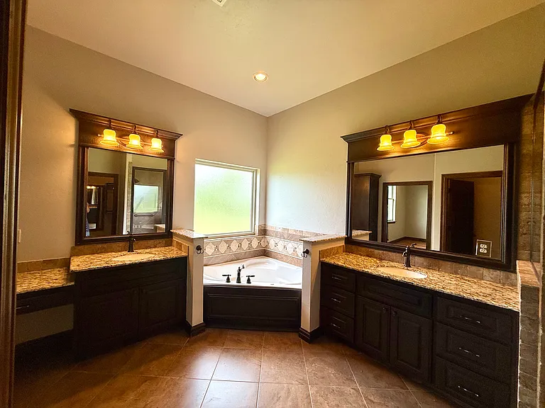 Beautiful granite countertops. To the left is a lower-level countertop for a vanity. Choose your favorite stool/chair to put on makeup.
