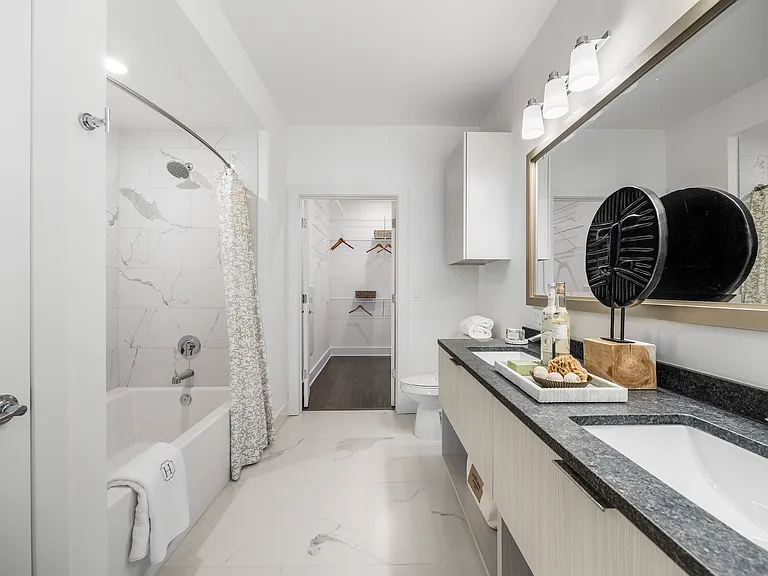 Elegant bathroom with marble tiles, stylish vanity, and walk-in closet access offering modern luxury.