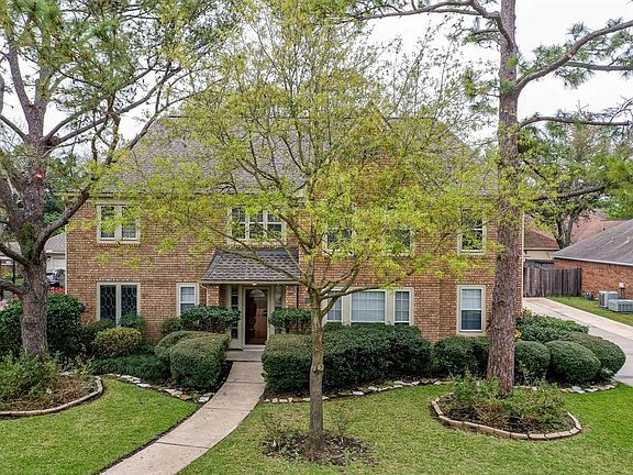 A large yard with winding sidewalk surrounded by mature trees and lush landscaping offers great curb appeal for this traditional style home!