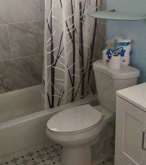 Remodeled hall bathroom with tiled floor, and shower walls.