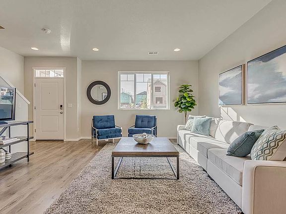 AI render. The living room and front door. Newer Wood Laminate flooring and a light and bright room.