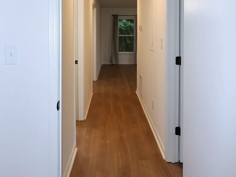 Hallway with Modern Lighting leading from Bedrooms to Living Room and Kitchen.