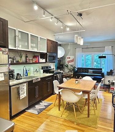 Open eat-in kitchen with open shelf, upgraded appliances and frosted cabinet fronts.