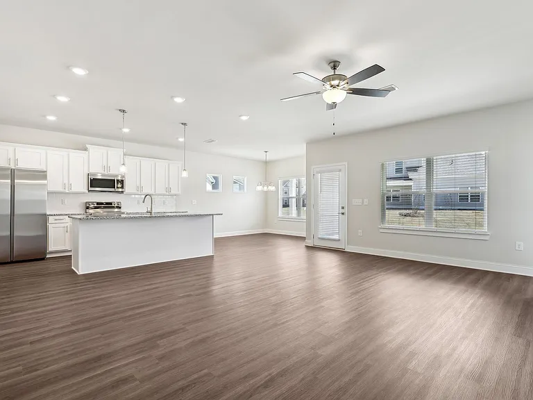 Spacious kitchen equipped with a refrigerator, sink, and ceiling fan.
