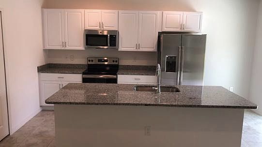 Open concept kitchen with a huge granite island and all stai