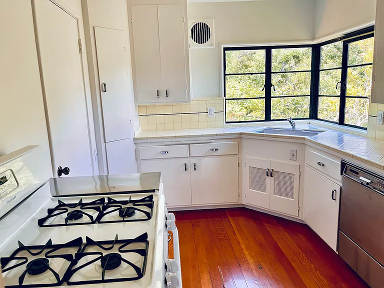 Kitchen with a window wrapped corner above the sink and gas stove, refrigerator and dishwasher