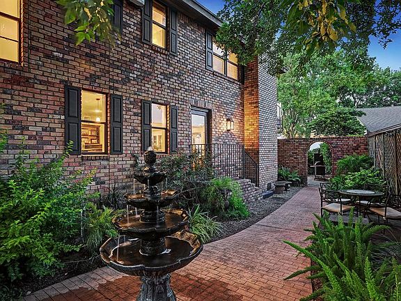 BRICK-LINED COURTYARD WITH FOUNTAIN SITS TO THE RIGHT OF THE ENTRY.