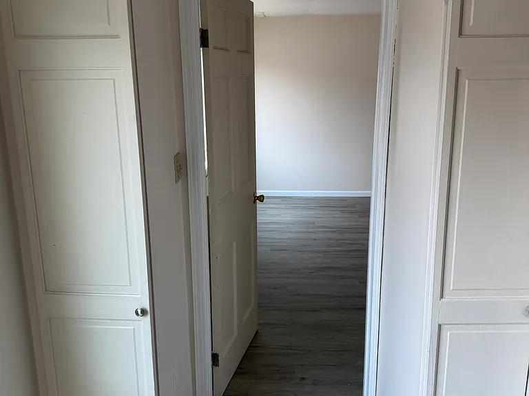 View of bedroom door from kitchen area. Also visible are built-in pantry closets.