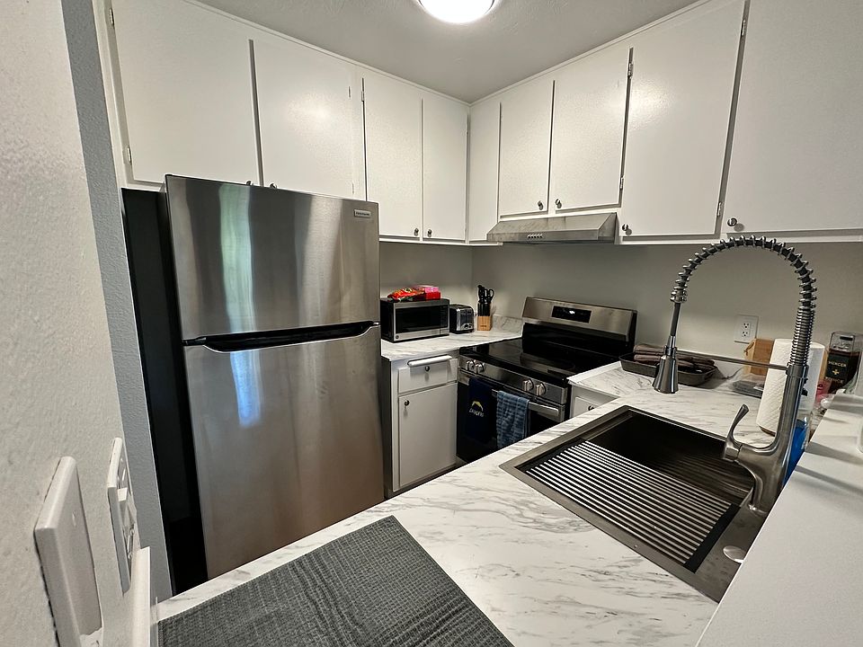 Kitchen includes refrigerator, oven/stove, and counterop microwave. High countertop for use with bar stools.