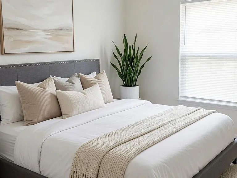 Well-appointed bedroom with a comfortable bed, bedside table, and a window with blinds for adjustable natural light.
