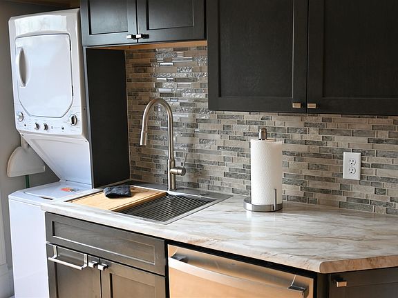 Kitchen with stainless steel workstation sink, dishwasher and washer/dryer.