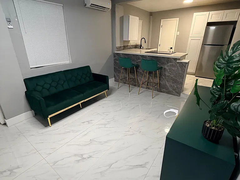 Open-concept living area with a breakfast bar, bar seating, and a full kitchen featuring ample cabinetry and stainless fridge