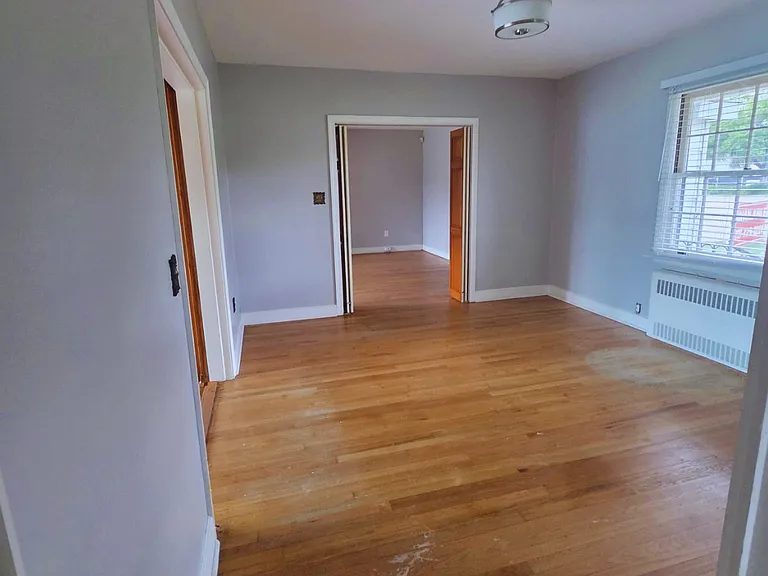 Large bedroom with bright windows and elegant ceiling light for added charm.