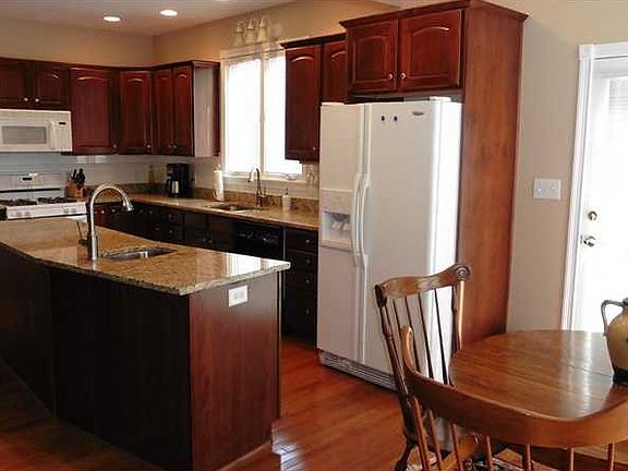 Kitchen. The Kitchen is light and bright and features hardwood flooring, a center island with bar sink, granite counters and doors leading to the back entertainment deck