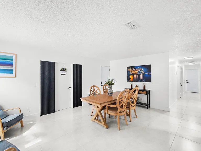 Open dining area with a full-size table, tile flooring, and convenient access to nearby rooms and hallway.