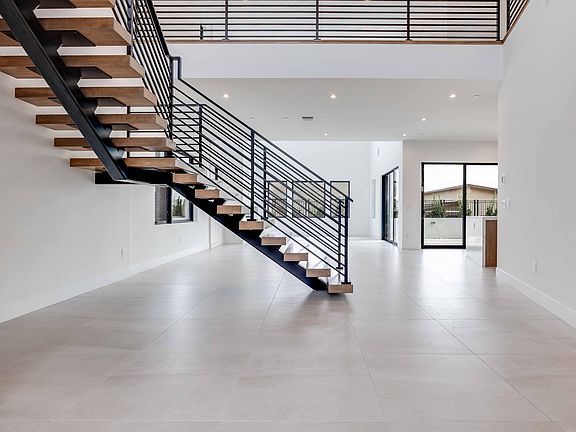 A modern, minimalist interior with a wooden staircase and metal railing leading to an upper level, s
