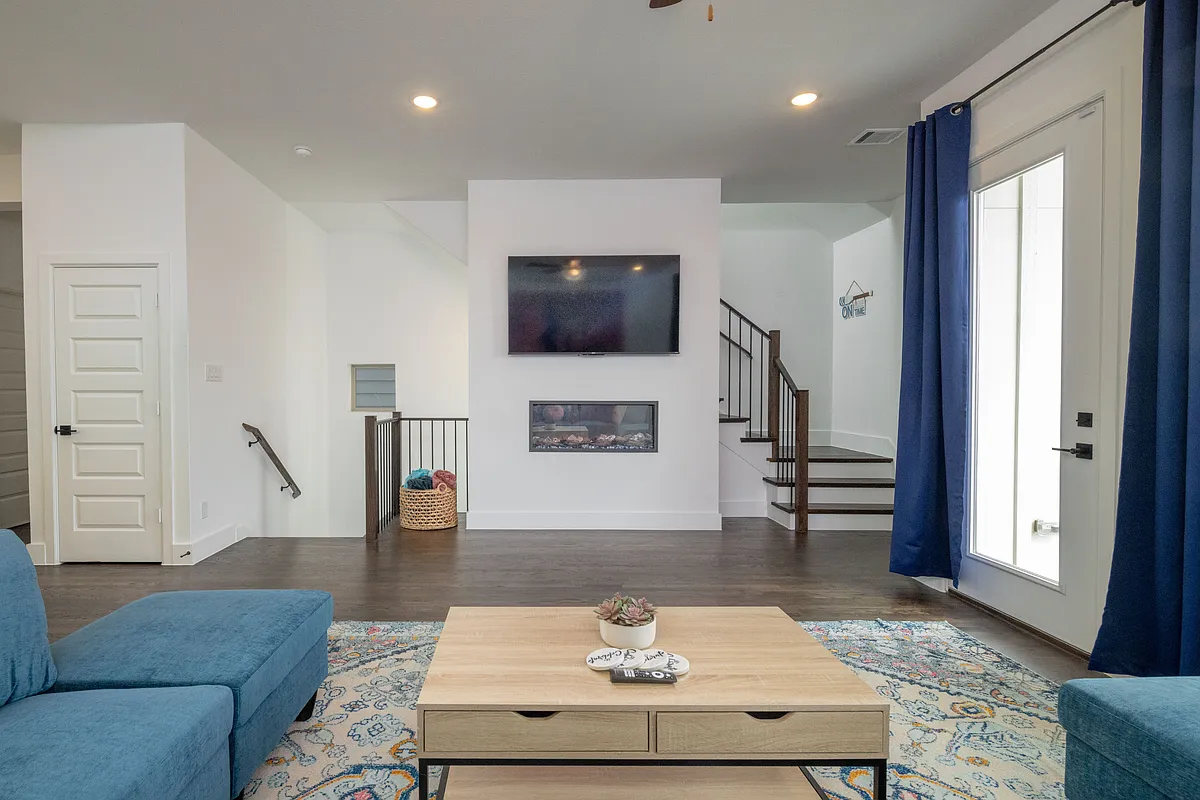 Spacious living room with vibrant pops of color, a large L-shaped couch, cozy fireplace, and TV_perfect for lounging and unwinding. - 9207 Easy St