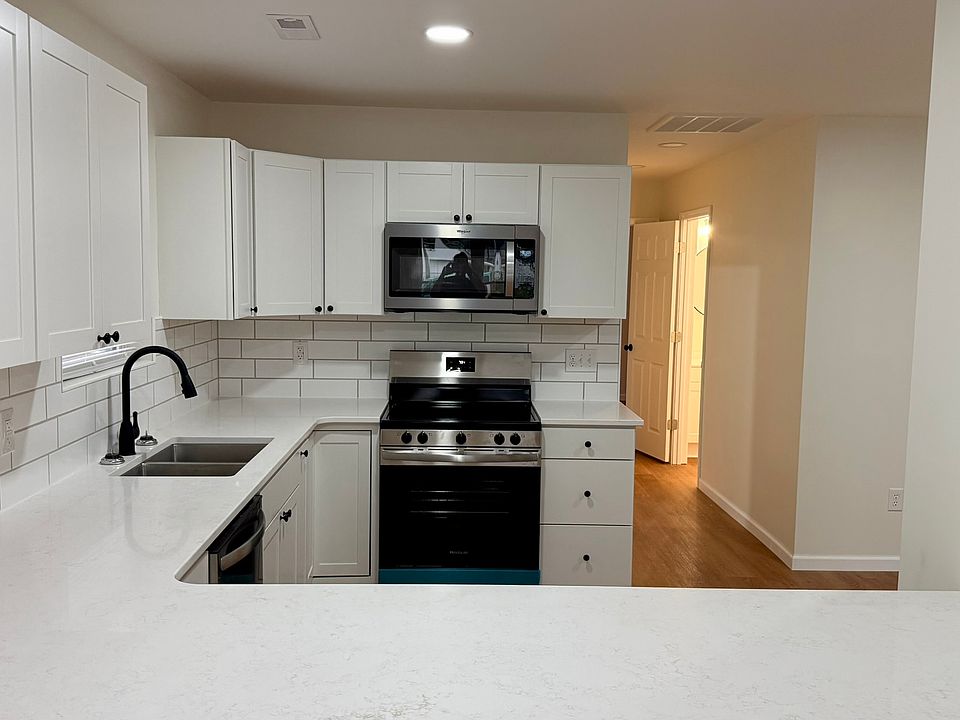 Modern open-concept kitchen featuring generous countertop space, abundant white cabinetry, subway-tile backsplash, stainless-steel appliances, built-in microwave, and a large peninsula perfect for dining or entertaining.