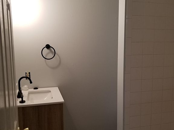 Basement bathroom. Standing tiled shower, toilet hidden behind the small tiled wall you see.
