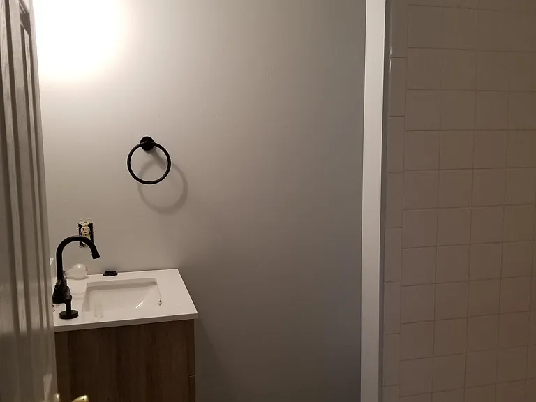 Basement bathroom. Standing tiled shower, toilet hidden behind the small tiled wall you see.