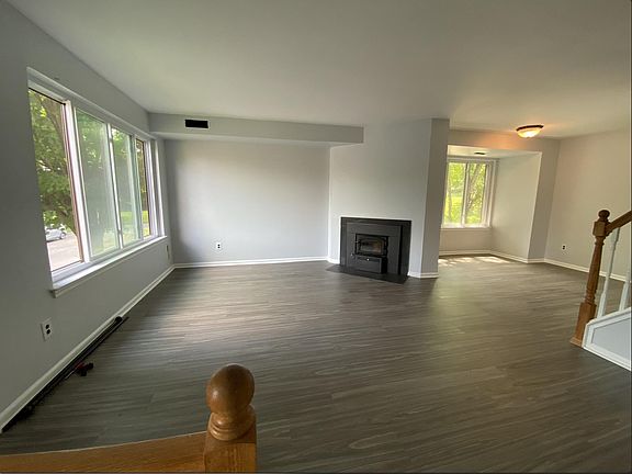 View is from front steps leading up from front door into open concept living room and dining room. Fireplace with wood burning insert pictured.