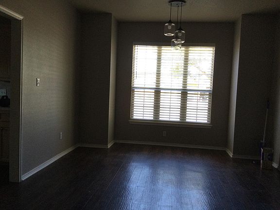 Dining area in open concept living room with wood blinds looking out into front yard