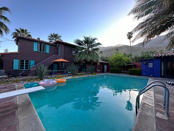 The main house and pool backyard when sun sets behind mountains