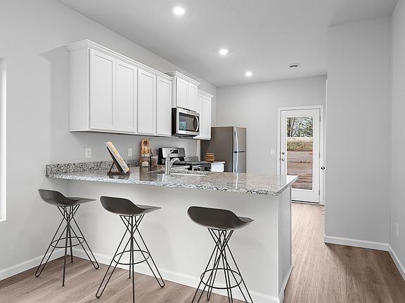 The kitchen has stainless steel appliances and plank flooring.