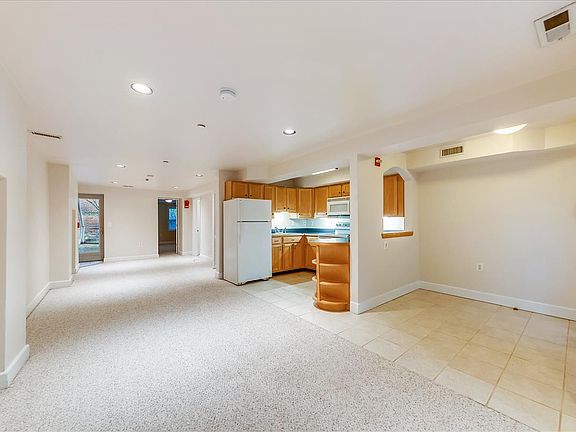 Panorama photo showing entry foyer, open kitchen, open living/dining area, back door to garden.