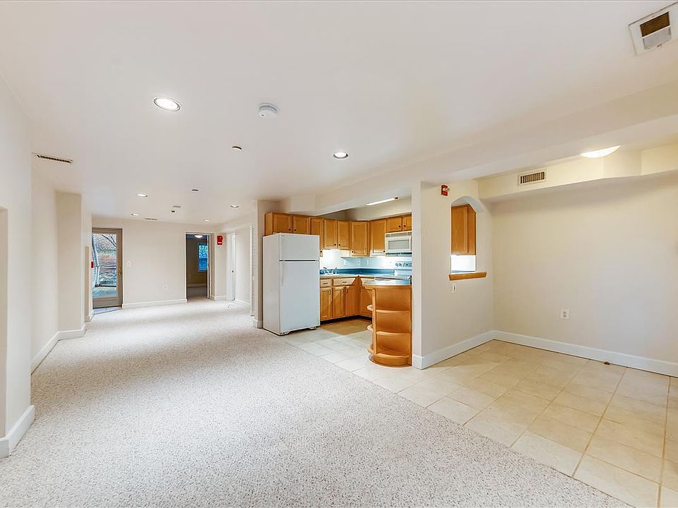 Panorama photo showing entry foyer, open kitchen, open living/dining area, back door to garden.