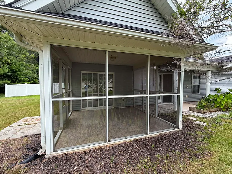 Enjoy indoor-outdoor living from the screened-in porch with elegant marble flooring, overlooking a spacious backyard that's perfect for relaxing or entertaining.