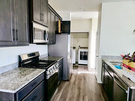 The modern kitchen, equipped with granite countertops, stainless steel appliances, and a gas range, seamlessly flows into the dining area and spacious great room, perfect for entertaining.