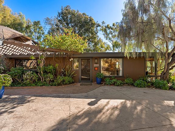 Welcoming front entrance surrounded by lush landscaping and mature trees.