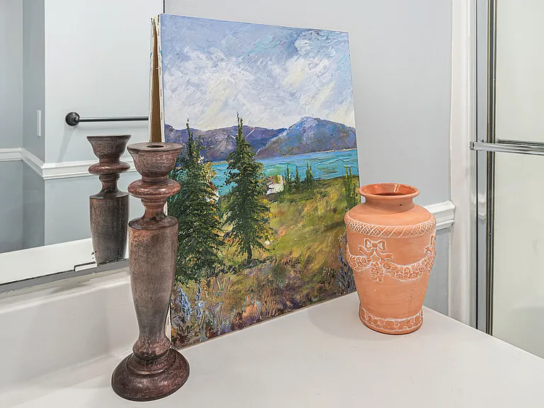 Thoughtful details like artwork, a vase, and a candle holder bring a refined and relaxing feel to this well-designed bathroom.