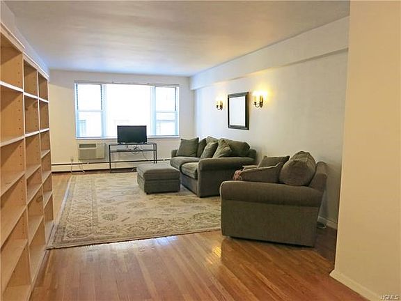 Large living room with huge window and hardwood floors.