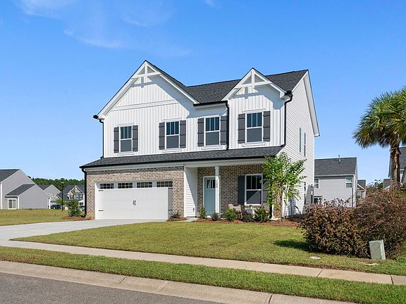 A large white house with black shutters is sitting on top of a lush green lawn.