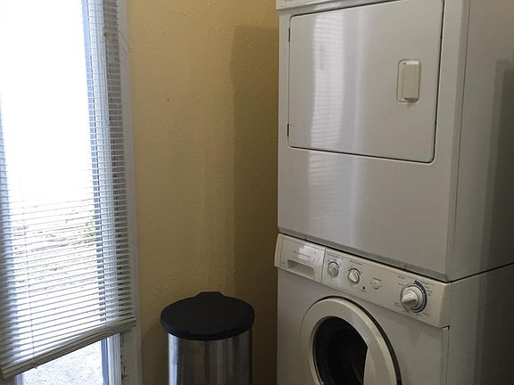 Stacked washer and dryer is located in a little alcove beside fridge.