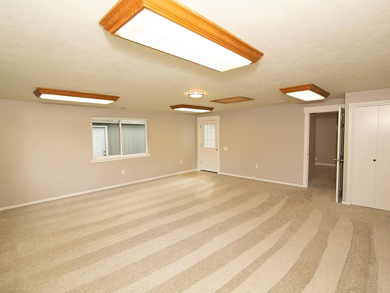 Extra Large Bonus room downstairs (converted garage), with a separate door to the side yard (left) and door to the front of the house (right, open)