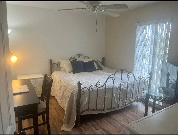 King size bed with new bedding with wrought iron frame. Desk and chair and dresser with TV.