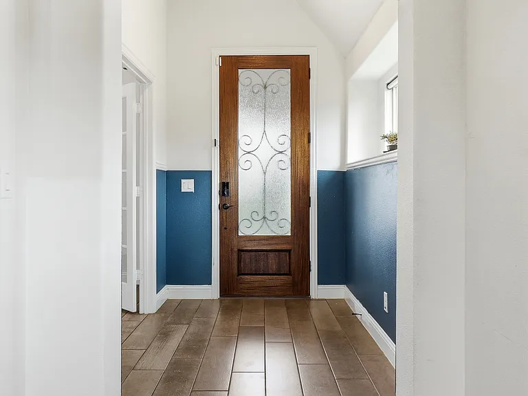 Entryway featuring a decorative wood-finish front door with privacy glass, wood-finish flooring, two-tone wall treatment, and a transom window