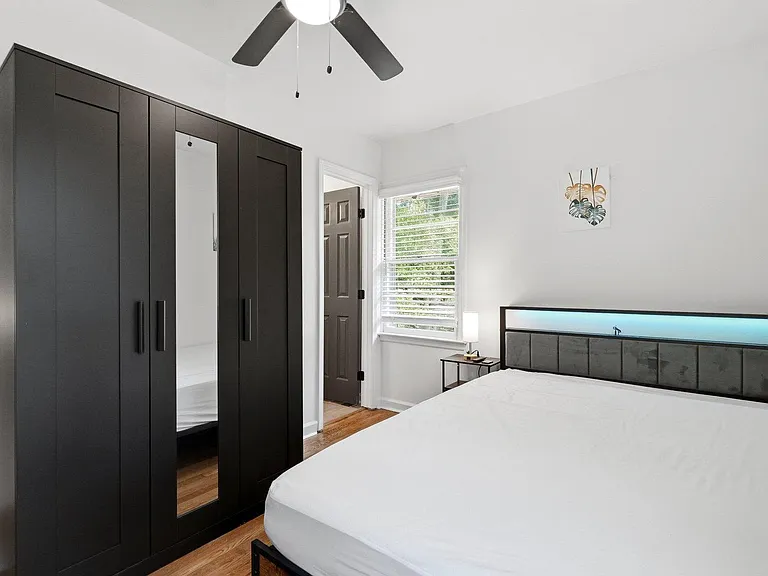 Private bedroom with a comfortable bed, large wardrobe storage, ceiling fan, and a window with blinds for natural light.