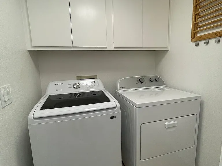 Laundry room with iron, ironing board, and hanging rack on the right.